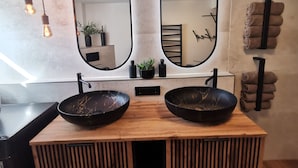 A bathroom with two black marble sinks, wooden vanity, and a large mirror. - Garden view apartment with pool and children's playground (Dippoldiswalde)