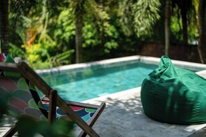 Relax by the pool surrounded by lush greenery and comfortable seating areas.