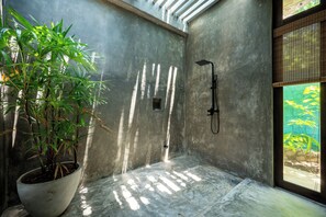 Shower area with a potted plant and natural light.