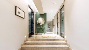 A hallway with marble steps, a round rug, a mirror, and framed pictures on the walls. - Pepys House: A Modern Touch of History (London)