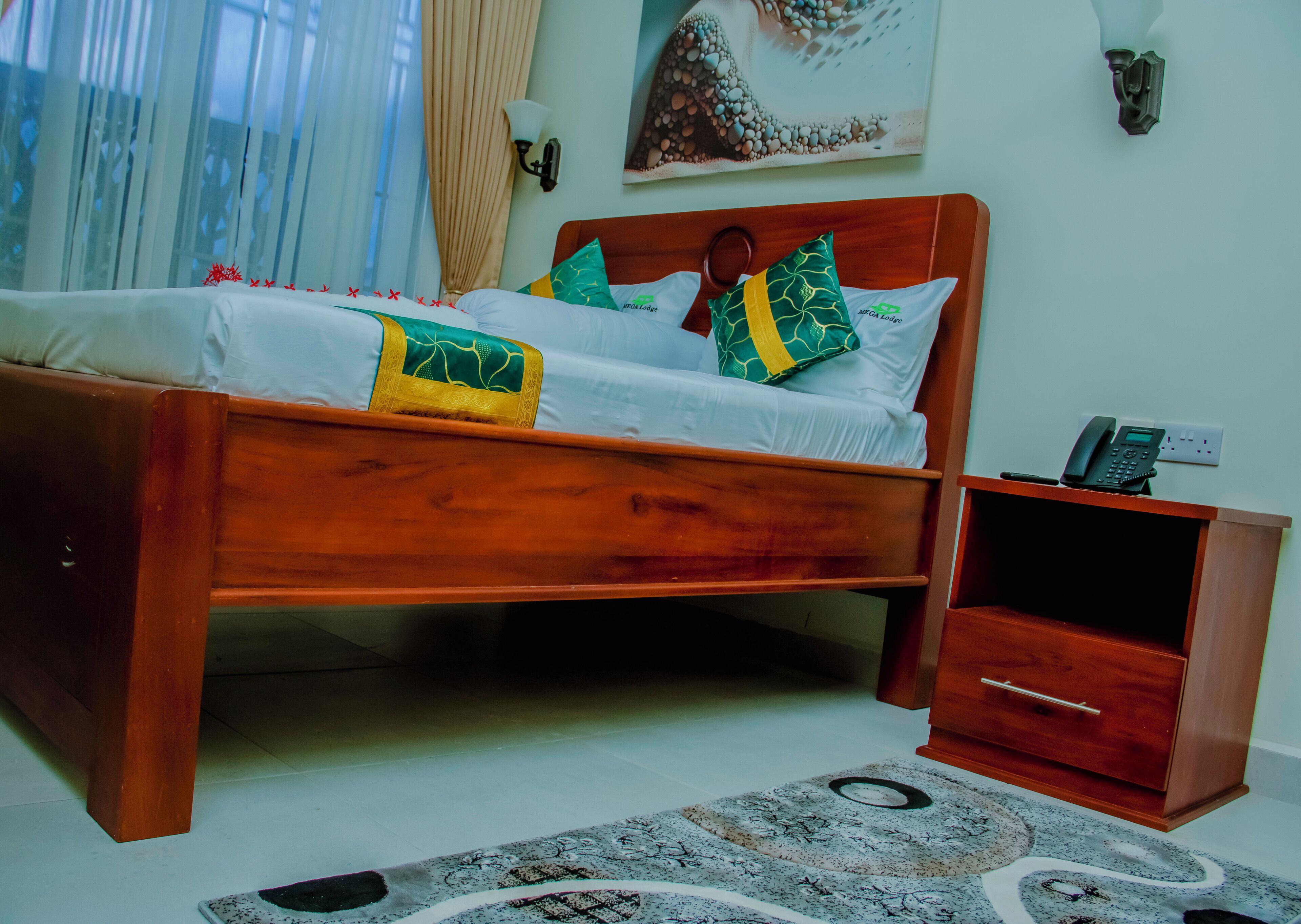A wooden bed with white bedding and decorative pillows, a bedside table with a phone, and a patterned rug on the floor.
