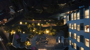 An aerial view of a rooftop garden with seating areas, a pool, and a building with multiple windows. - Kandy Myst by Cinnamon (Kandy)