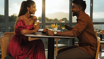 Un couple est assis à une table, dînant et profitant de la vue sur l’extérieur.