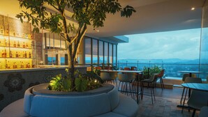 A modern bar area with a seating arrangement, a large tree planter, and a view of the cityscape. - Kandy Myst by Cinnamon (Kandy)
