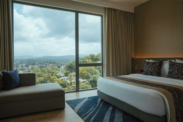 A hotel room with a large window, a bed, a sofa, and a view of a cityscape. - Kandy Myst by Cinnamon (Kandy)