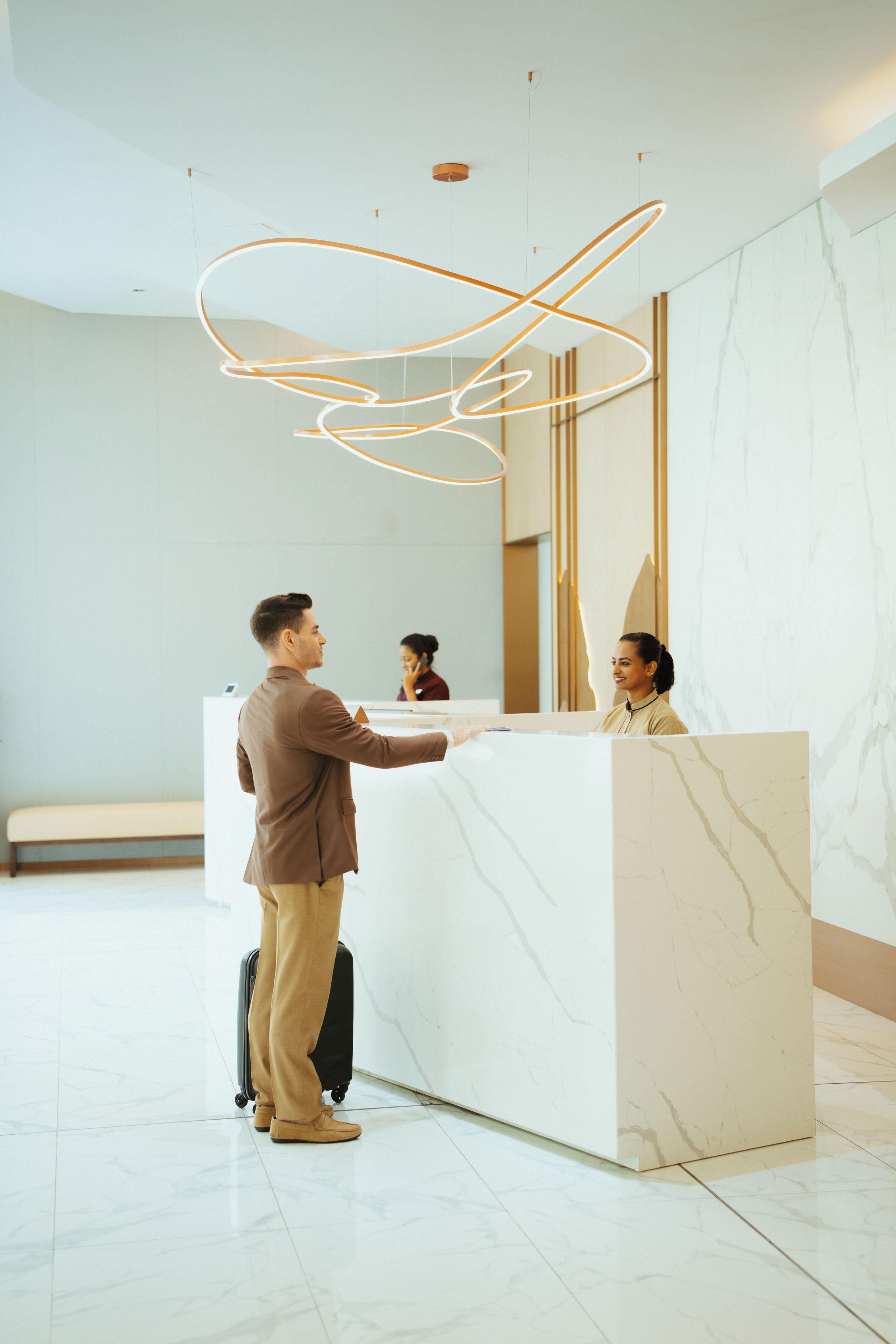 A reception area with a marble reception desk, a modern light fixture, and a seating area with a bench.