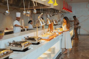 A buffet setup in a commercial kitchen with stainless steel appliances and hanging pots. - Kandy Myst by Cinnamon (Kandy)