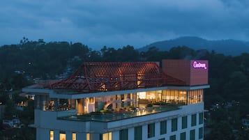 A hotel with a rooftop terrace, a prominent red structure, and a neon sign.
