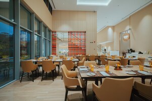Un comedor moderno con varias mesas y sillas, ventanas amplias y vistas al exterior.
