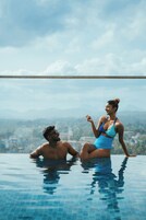 A couple in a swimming pool with a cityscape view.