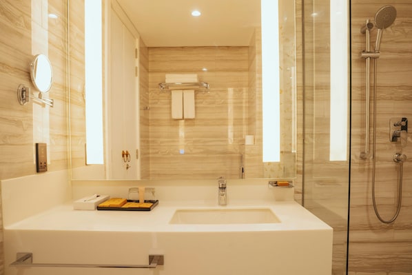 A modern bathroom with a large mirror, a sink, a glass-enclosed shower, and a marble wall. - Kandy Myst by Cinnamon (Kandy)