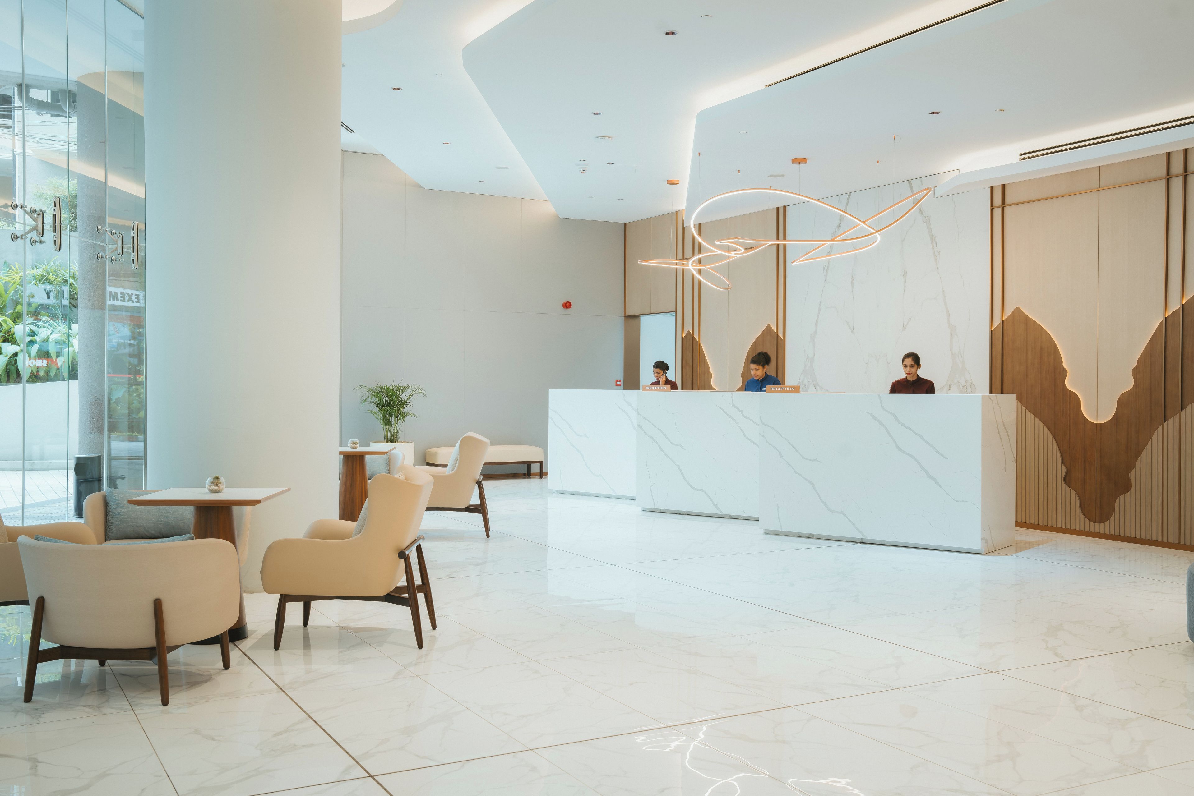 Un moderno vestíbulo de hotel con mostrador de recepción, zona de estar y un amplio ventanal.