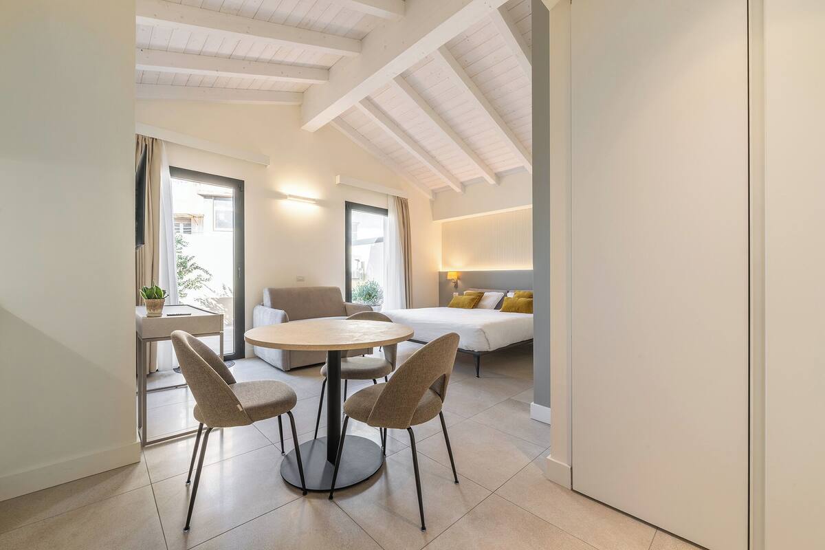 A modern living room with a round table and chairs, a sofa, and a bed.