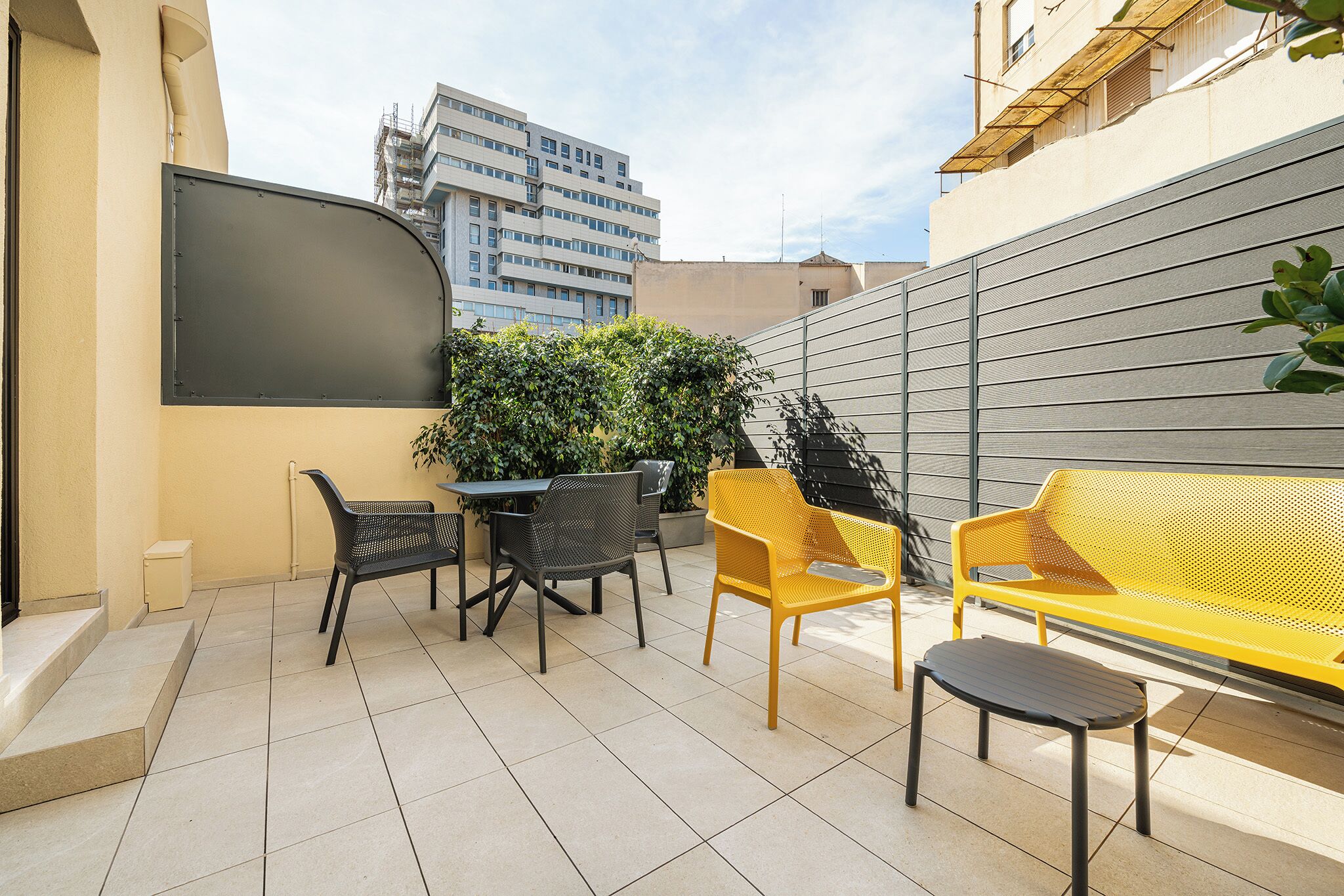 Un patio con una mesa, sillas y un sofá amarillo.
