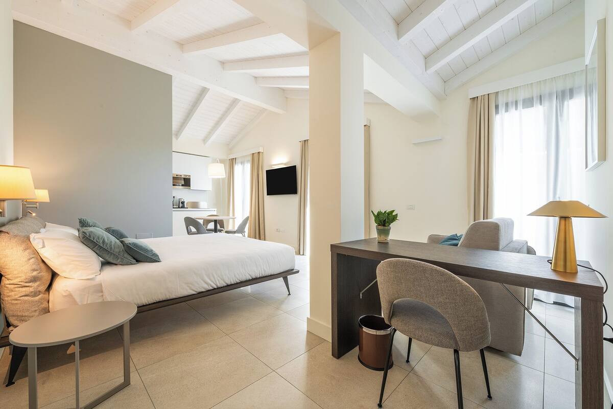 A modern hotel room with a bed, desk, and seating area.