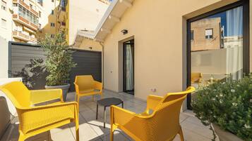 Un balcon avec des fauteuils en osier jaune, une petite table et une plante en pot.