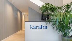 Un comptoir d’accueil portant l’inscription « karalín SONNINO SUITES » et, à sa droite, une grande plante en pot.