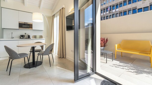 Une cuisine moderne avec un coin repas, un banc jaune et une vue sur un immeuble doté de fenêtres.