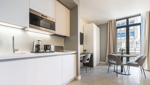 Une cuisine moderne équipée d’un four et d’un micro-ondes encastrés, d’une machine à café et d’un coin repas avec deux chaises et une table.