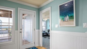 Un pasillo con una puerta que da a una habitación, una obra de arte enmarcada en la pared y un felpudo en el suelo.