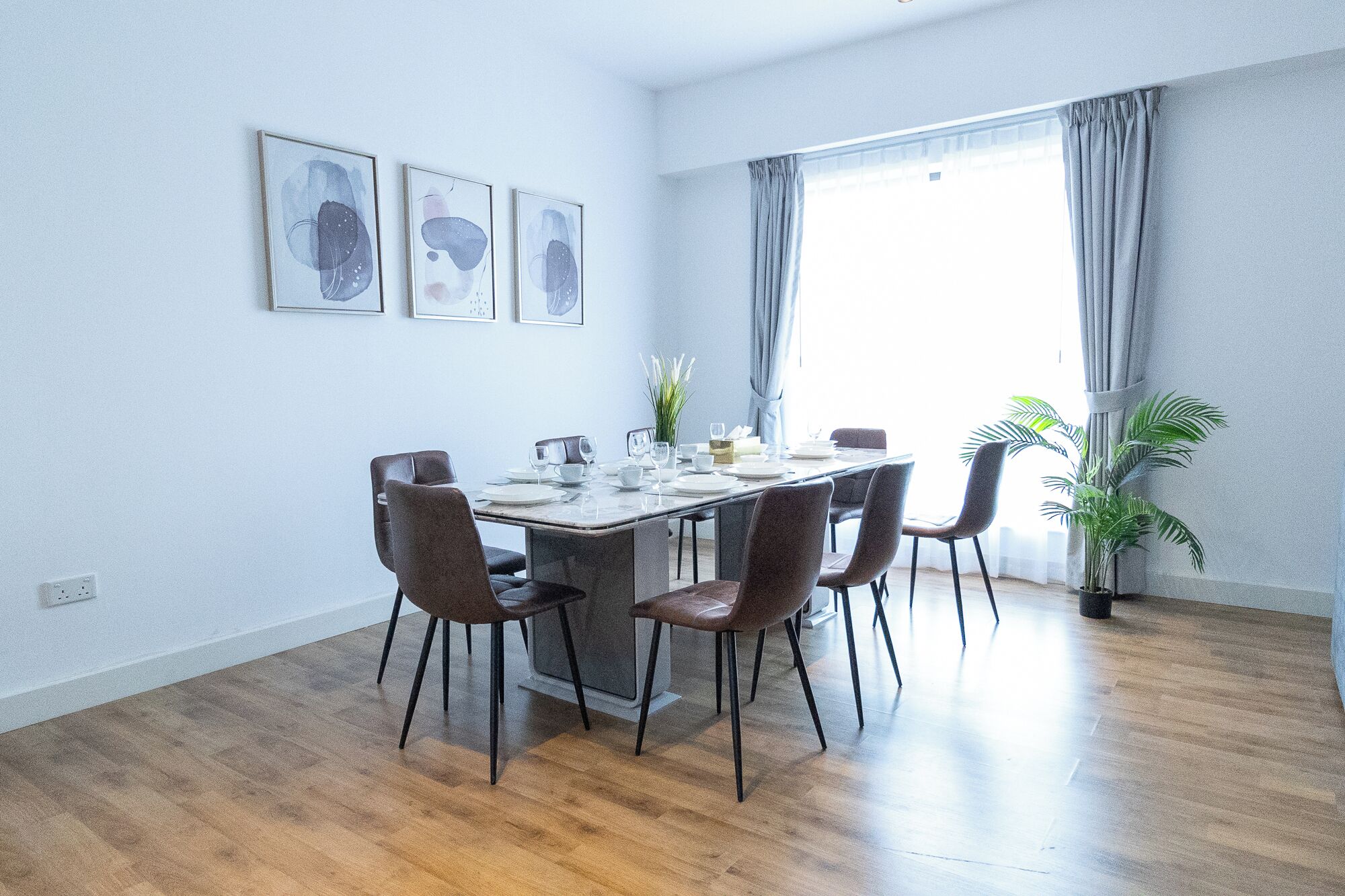 A dining area with a wooden table, six chairs, and a window with curtains.