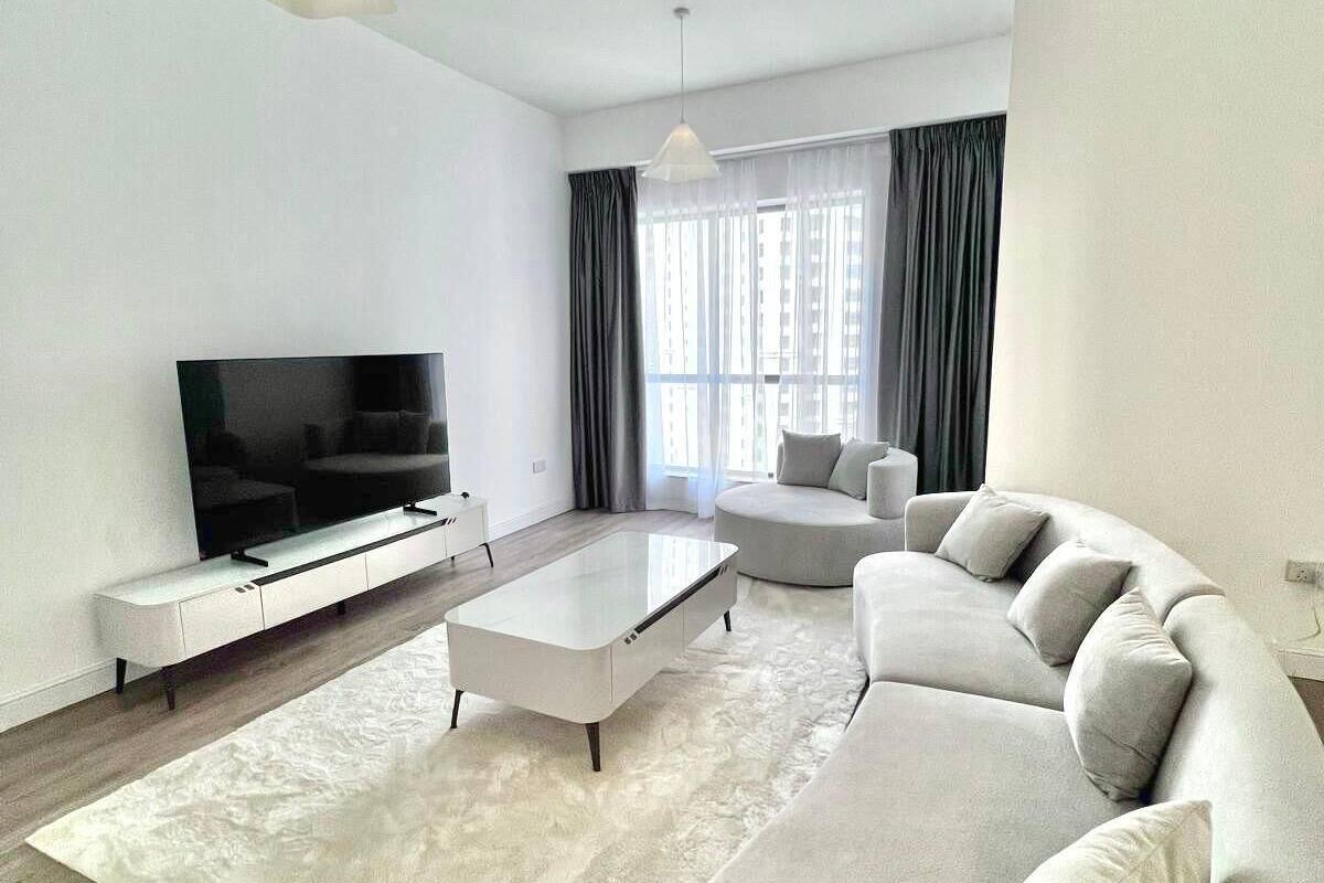 A modern living room with a large flat-screen TV, a white sofa, and a coffee table.