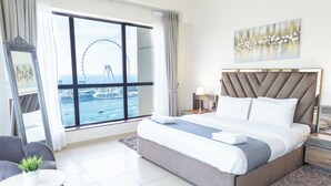 A hotel room with a large bed, a view of a Ferris wheel, and a cityscape. - HAPPY SEASON | JBR Apartments  (Dubai)