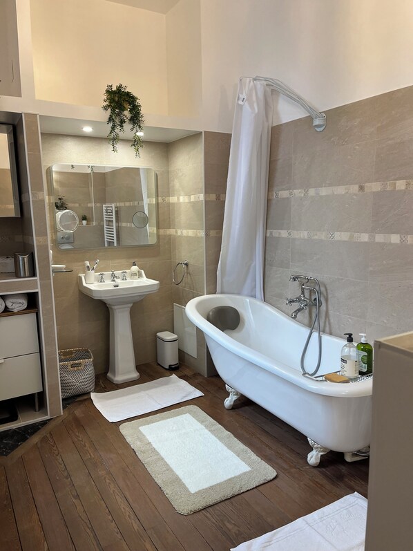 A modern bathroom with a freestanding bathtub, a pedestal sink, and a mirror with a towel rack.