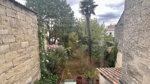 Une cour dotée d’un sol en verre, entourée de murs de pierre et d’arbres.