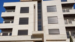 Un immeuble à plusieurs étages doté d’une architecture moderne, caractérisé par un élément vertical central et de nombreux balcons.