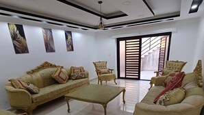 Un salon spacieux avec un plafond haut, une grande fenêtre et un escalier menant à l’étage supérieur.