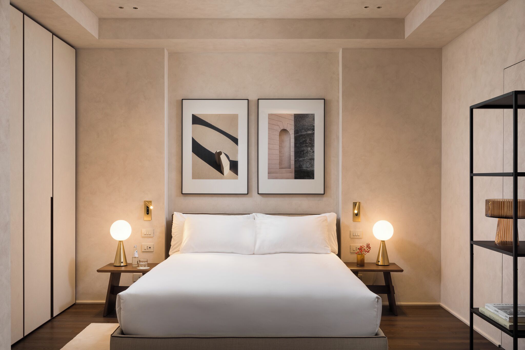Un dormitorio moderno con una cama grande, dos mesitas de noche con lámparas y dos cuadros enmarcados en la pared.
