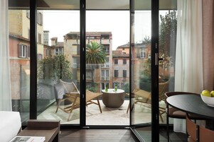 Un balcón con sillas de mimbre, una mesa redonda y vistas a edificios cercanos.
