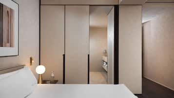 Een moderne hotelkamer met een groot bed, een nachtkastje met een lamp en uitzicht op een badkamer.