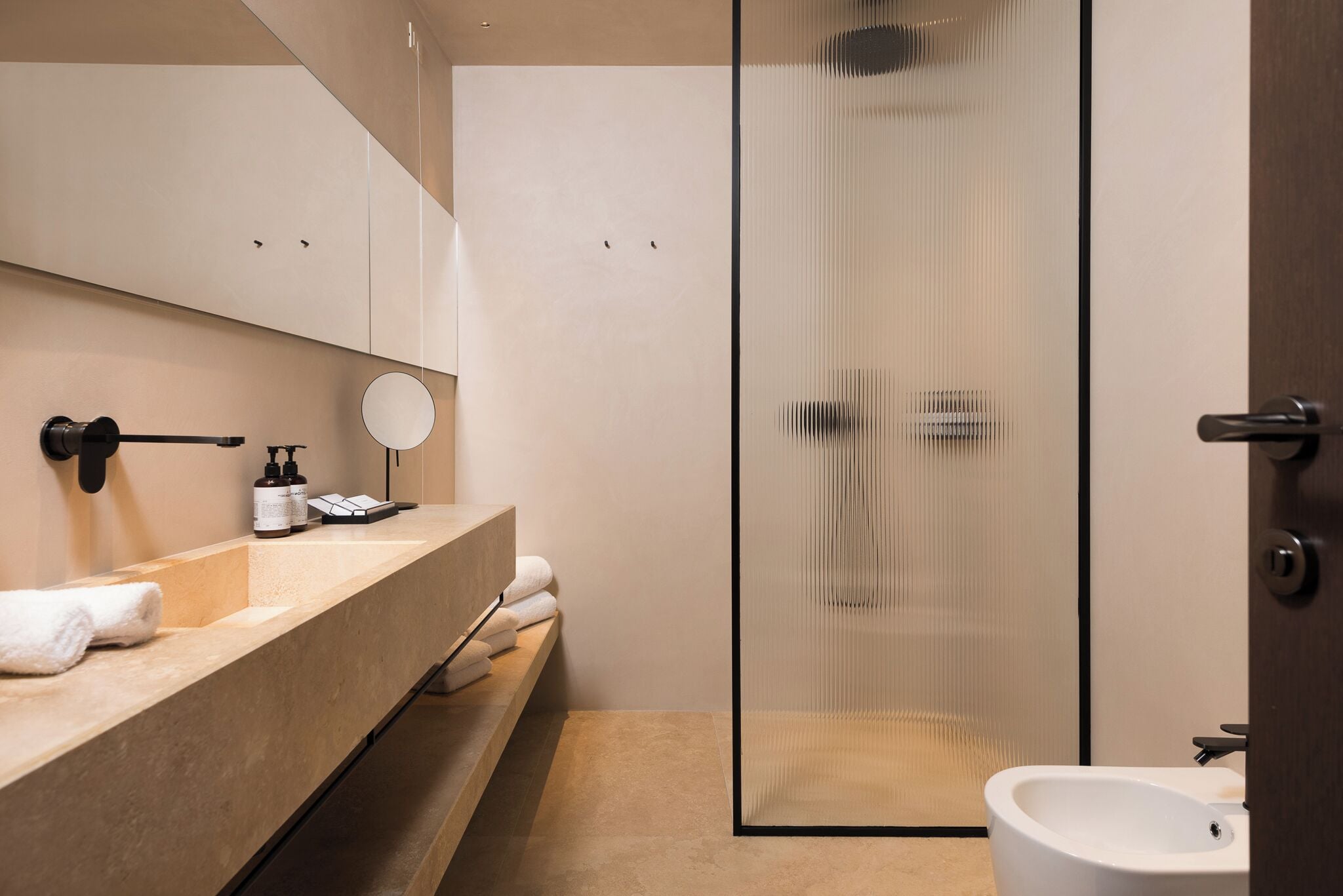 A modern bathroom with a glass shower enclosure, a sink with a mirror, and a toilet.