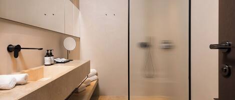 A modern bathroom with a glass shower enclosure, a sink with a mirror, and a toilet.