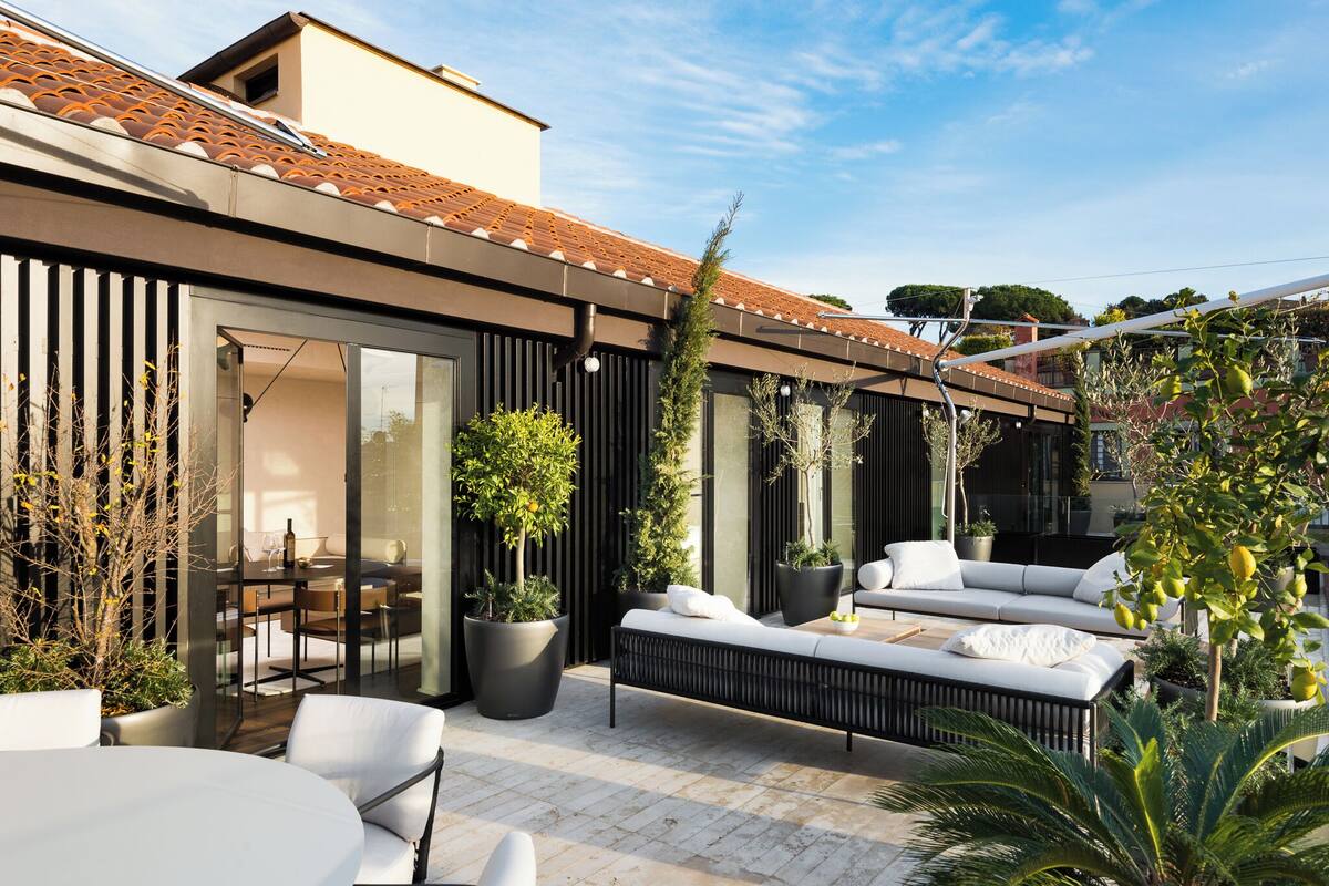 A modern outdoor patio with a dining area, seating, and potted plants.