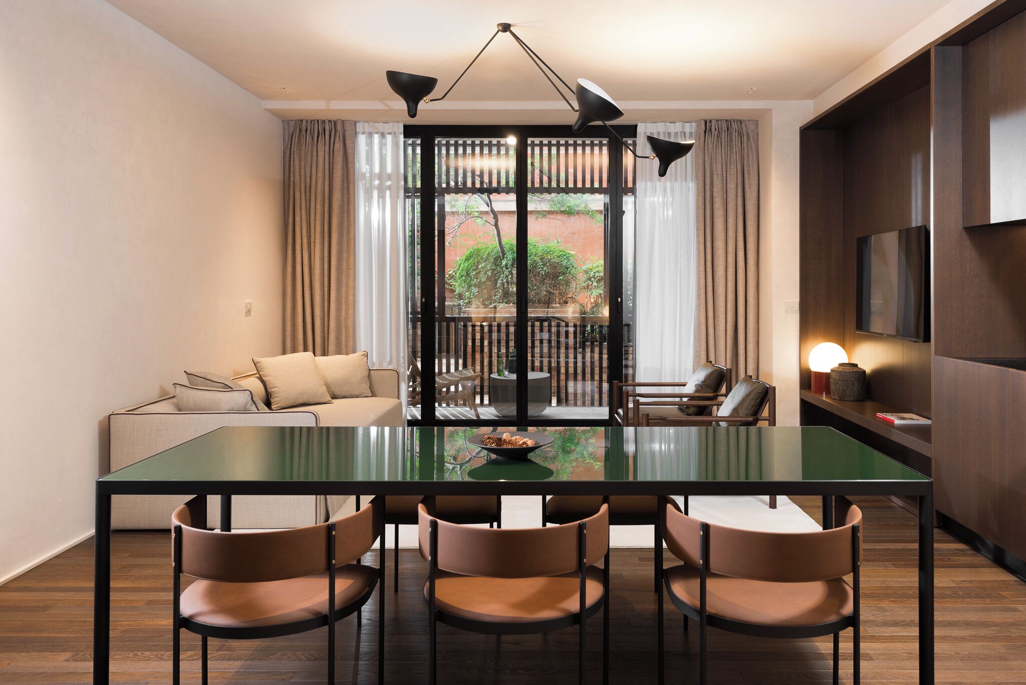 Zona pranzo moderna con tavolo in vetro, quattro sedie, un divano e un balcone con vista.