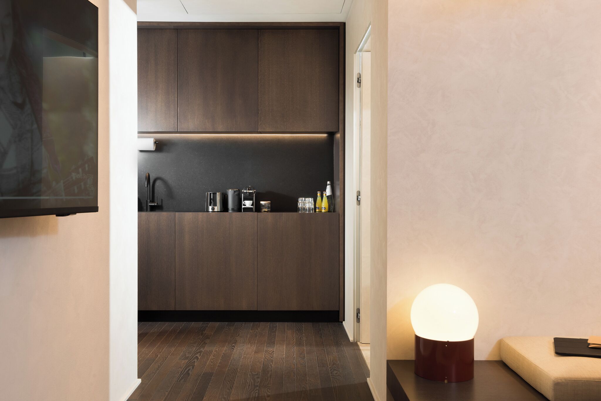 A modern kitchen with dark wood cabinets, a built-in oven, and a countertop with kitchenware.