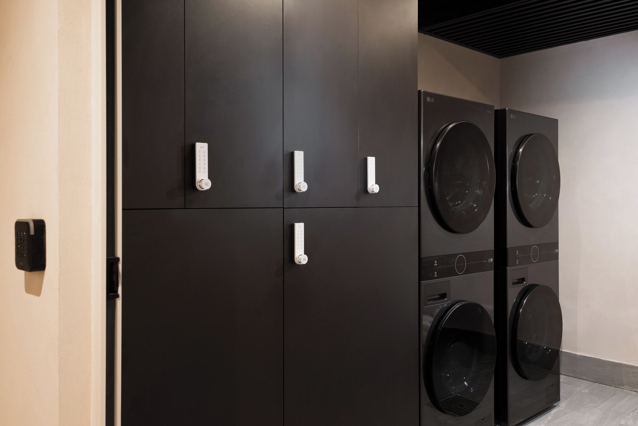 A laundry facility with four black cabinets and two front-loading washing machines.