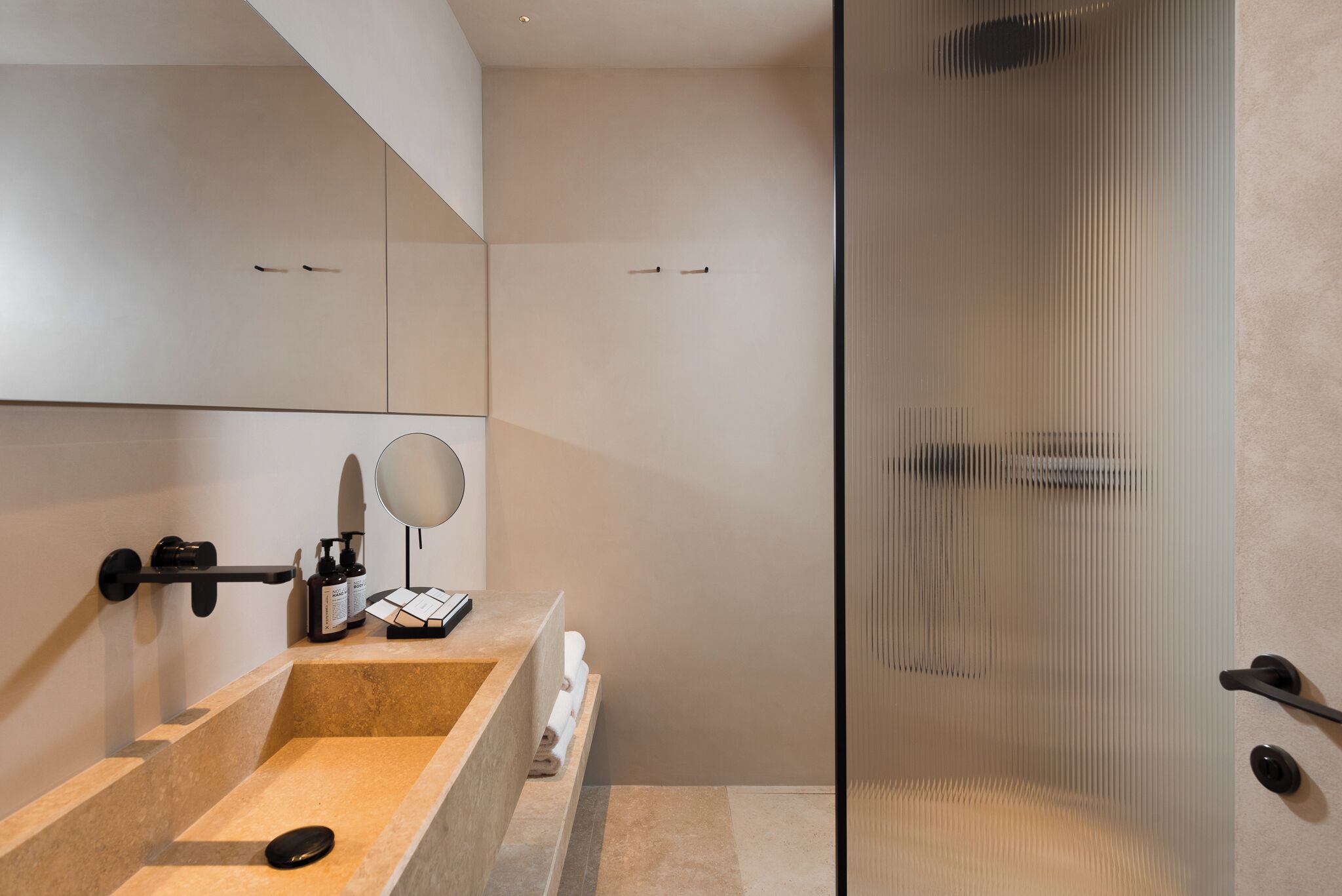 A modern bathroom with a large mirror, a sink, and a shower area.