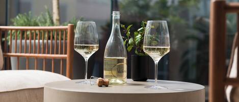 A table with two glasses of white wine, a bottle, and a cork.