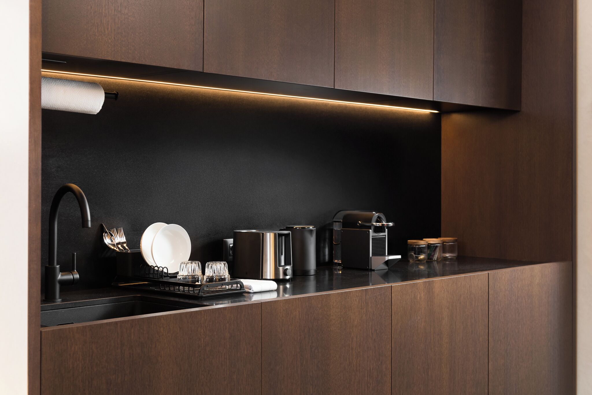 A modern kitchen with a dark wood finish, stainless steel appliances, and a sleek countertop.