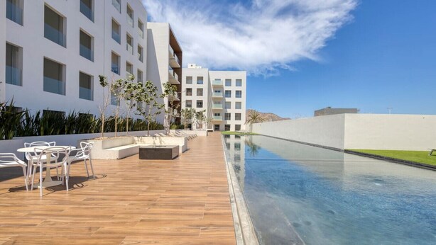 Un hotel moderno con zona de piscina, mobiliario exterior y vistas del paisaje circundante.