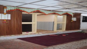 A covered porch with a wooden door and window, decorated with hanging ornaments. - Hotel Sun Up (Nashik)