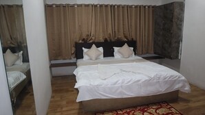A bedroom with a bed, curtains, and a wooden floor. - Hotel Sun Up (Nashik)