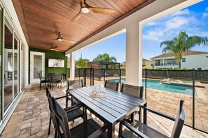 A covered patio area with a pool, outdoor seating, and a ceiling fan. - Arcades, Bocce, Haunted Mansion Theater, Cabana, Enchanted Forest: Great Escape (Kissimmee)