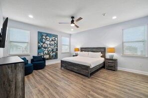 A bedroom with a wooden floor, a bed with white bedding, a ceiling fan, and a painting on the wall. - Arcades, Bocce, Haunted Mansion Theater, Cabana, Enchanted Forest: Great Escape (Kissimmee)