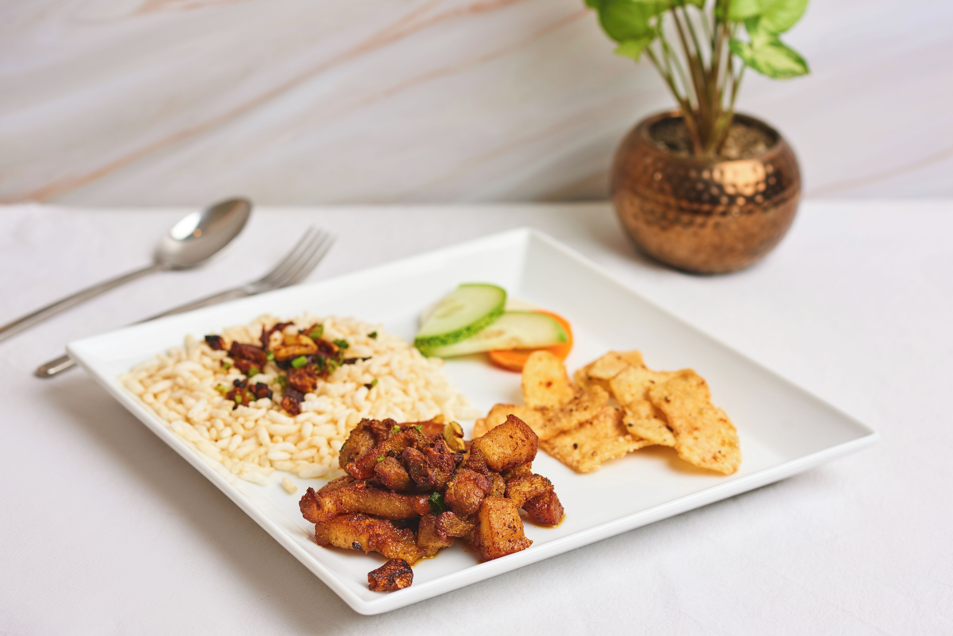 A white plate with rice, fried chicken, and chips.