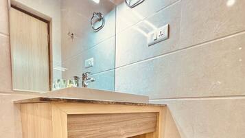 A bathroom with a wooden vanity, a mirror, a sink, and a towel shelf.
